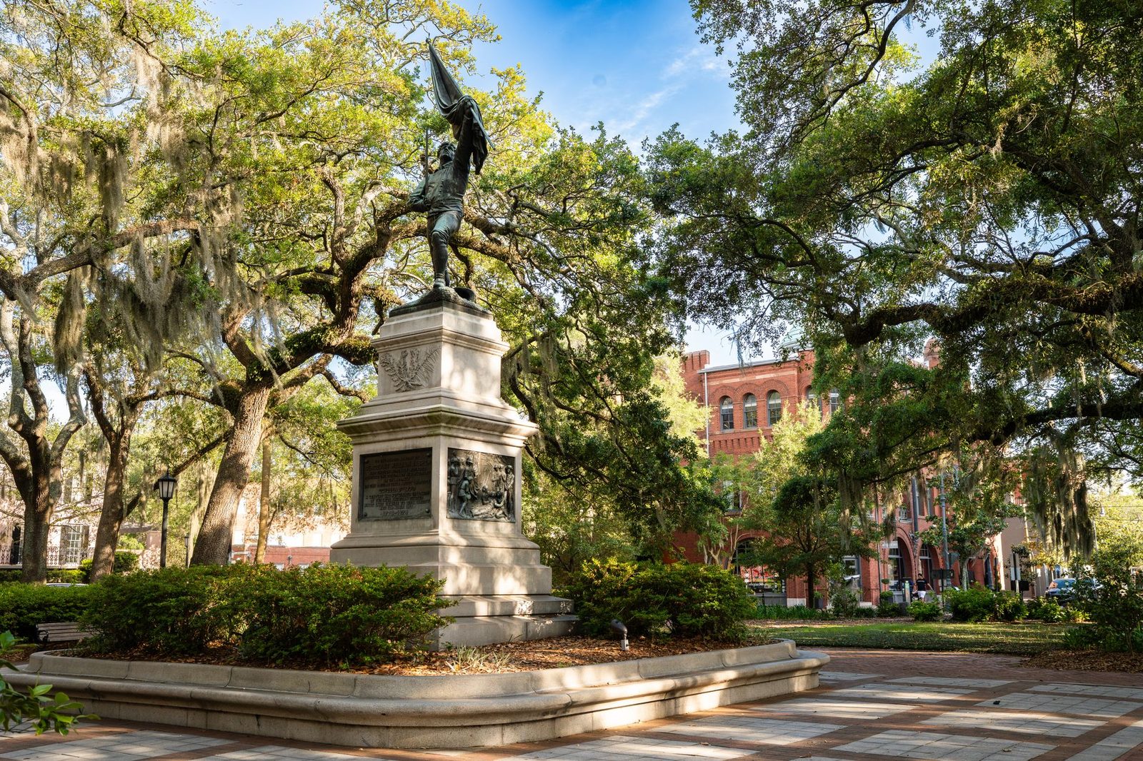 A monument under live oaks draped in Spanish moss in a Savannah, Georgia square
